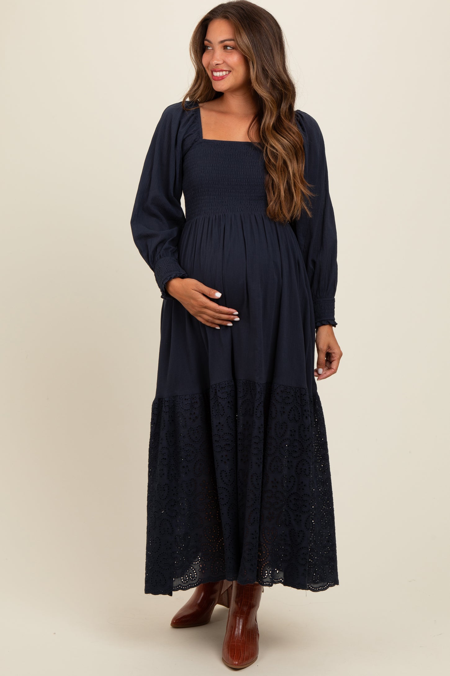 woman wearing a dark blue maternity maxi dress with smocked bodice and lace detailing, showing her baby bump