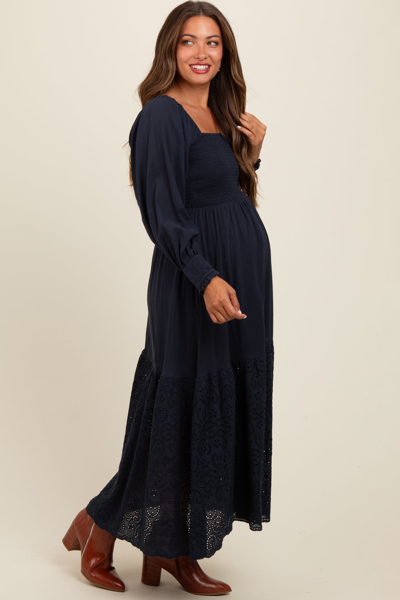 woman wearing a navy blue maternity maxi dress with a smocked bodice and embroidered hem, showing her baby bump