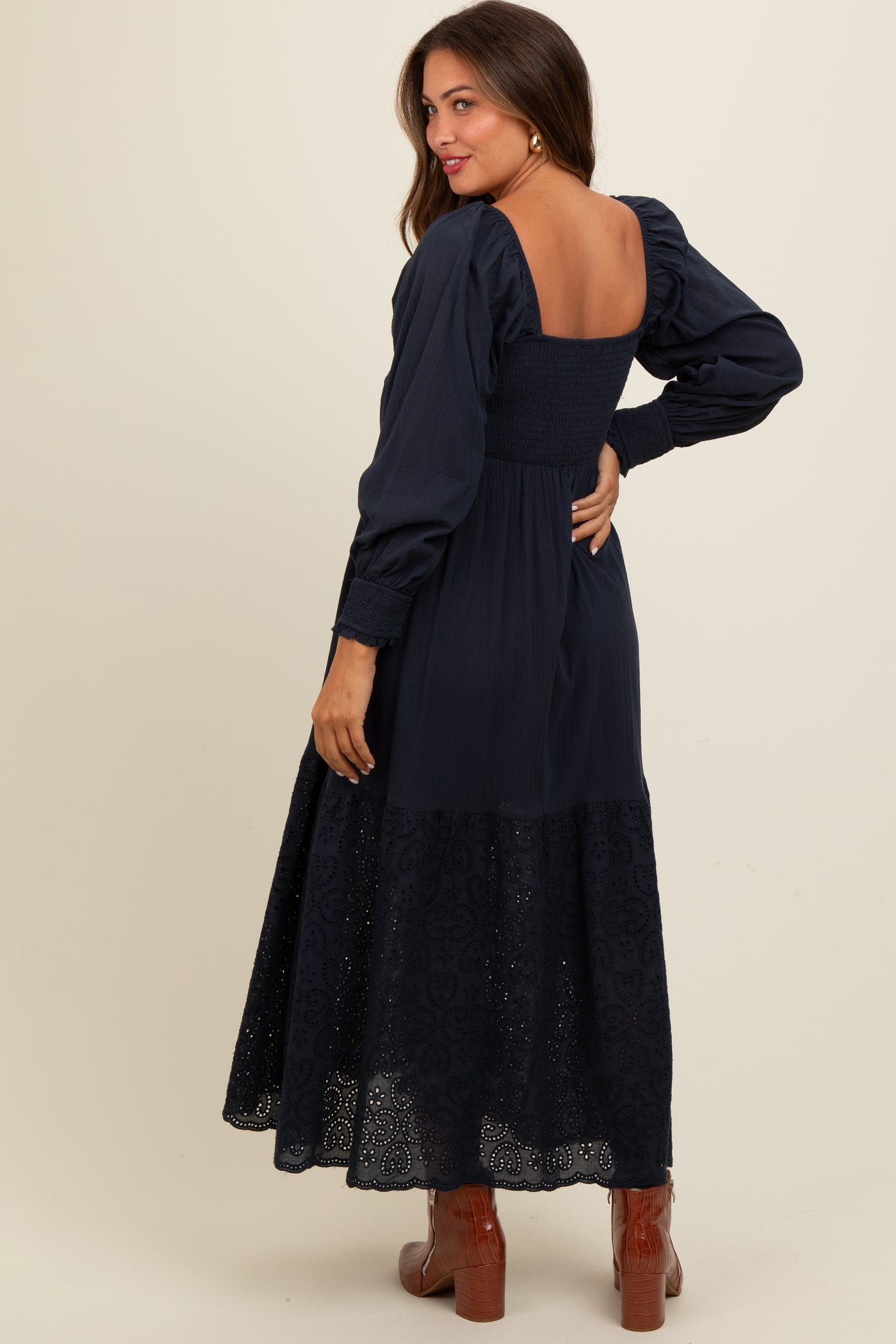 woman wearing a navy blue maternity dress with a smocked bodice and puff sleeves, featuring a lace hem detail