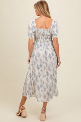woman wearing a light floral print maternity dress with puff sleeves and back smocking, showing a baby bump