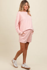 woman wearing a pink checkered maternity sweatshirt and matching shorts with a relaxed fit