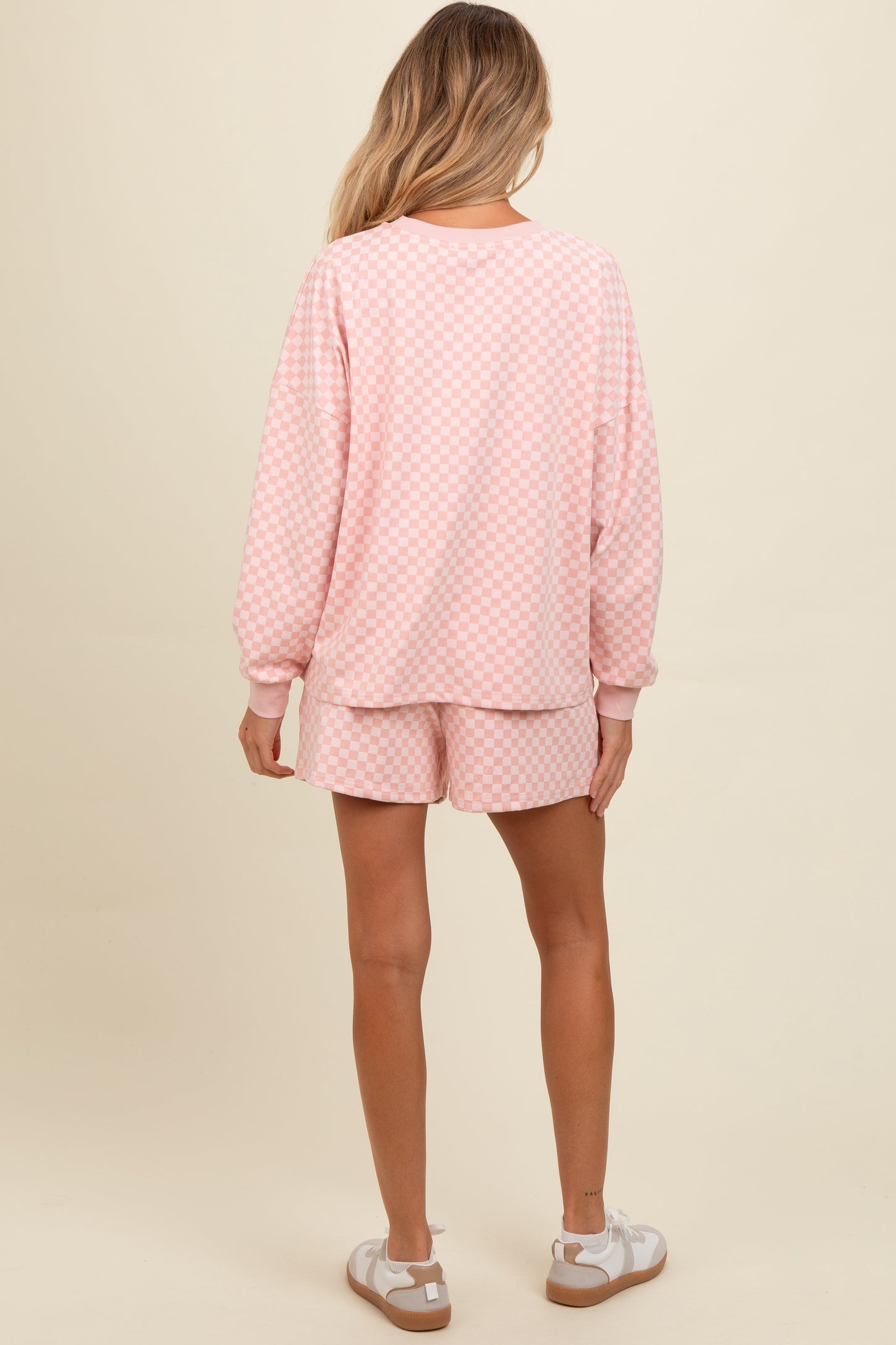 woman wearing a pink checkered maternity loungewear set with long sleeves and shorts, showing a relaxed fit