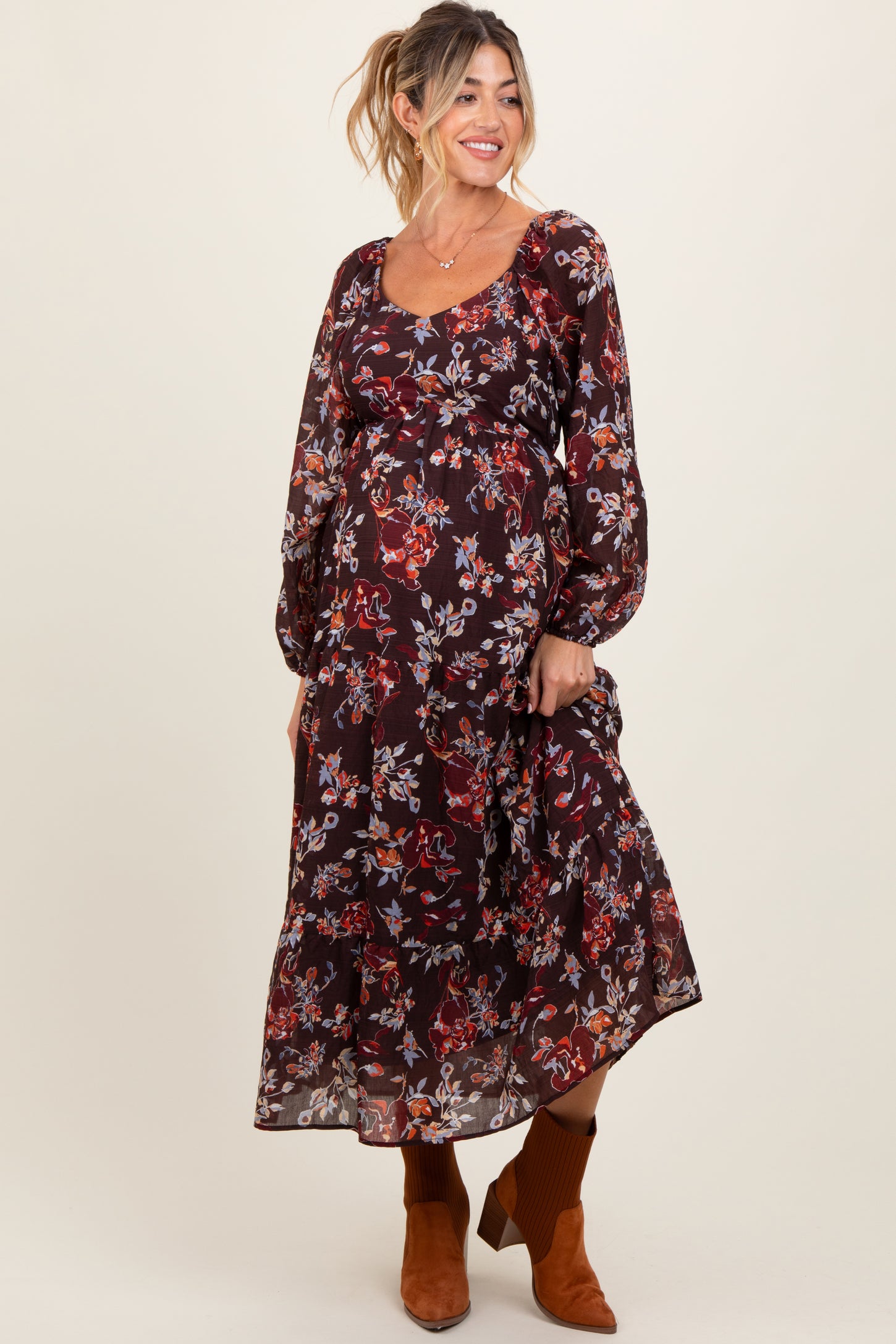 woman wearing a burgundy floral print maternity maxi dress with long sleeves and a baby bump visible