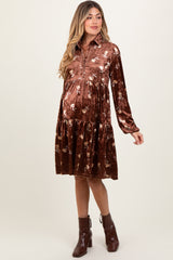 woman wearing a brown velvet maternity dress with floral print and a tiered skirt, showing her baby bump