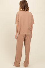woman wearing a beige ribbed two-piece loungewear set with short sleeves and wide-leg pants, shown from the back