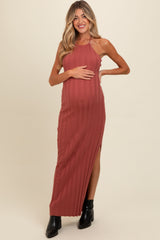 woman wearing a rust ribbed maternity maxi dress with side slits and holding her baby bump