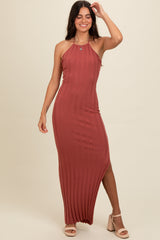 woman wearing a rust ribbed halter neck maxi dress and nude heeled sandals, posing with one hand on her hair