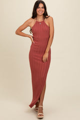 woman wearing a rust-colored ribbed halter neck maxi dress with a side slit and strappy heels