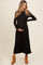 woman wearing a black ribbed maternity maxi dress and holding her baby bump, paired with tan ankle boots