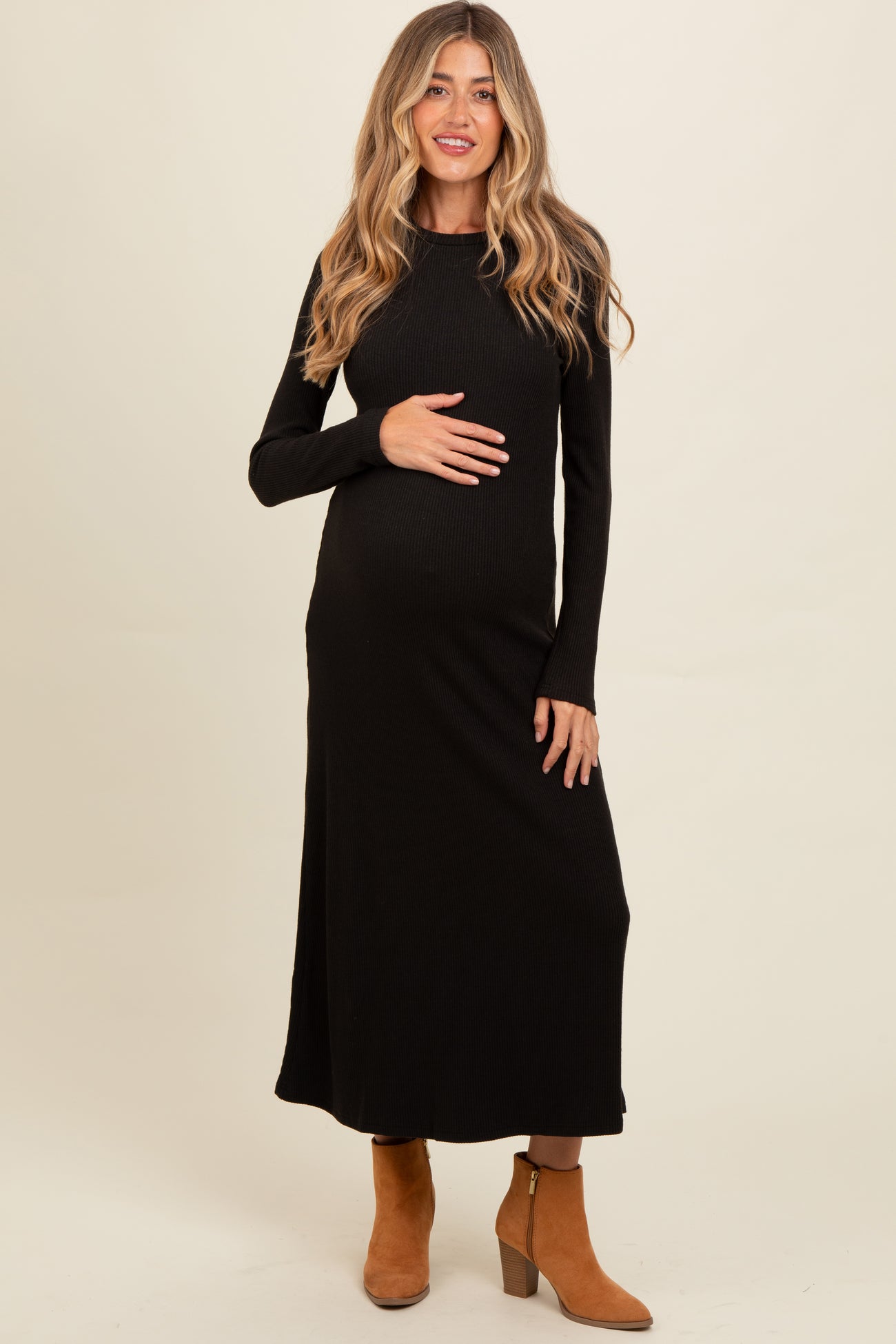 woman wearing a black long sleeve ribbed maternity dress and holding her baby bump