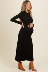 woman wearing a black long sleeve ribbed maternity dress and holding her baby bump