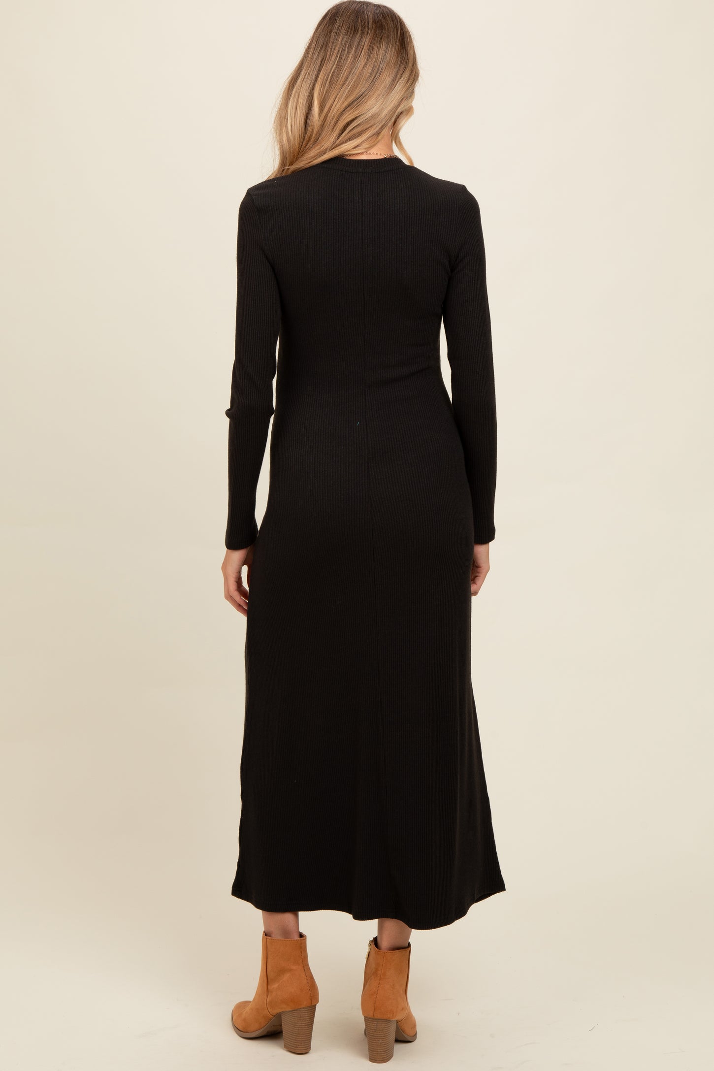 woman wearing a black ribbed maternity maxi dress, showing the back view, paired with brown ankle boots