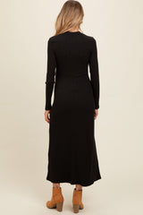 woman wearing a black ribbed maternity maxi dress, showing the back view, paired with brown ankle boots