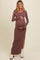 woman wearing a brown ribbed maternity maxi dress with long sleeves and a side slit, holding her baby bump