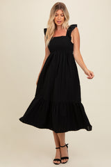 woman wearing a black midi dress with ruffle straps and a tiered skirt