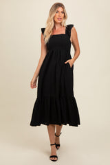 woman wearing a black ruffled sleeve midi dress with a tiered skirt and pockets