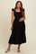 woman wearing a black maternity dress with ruffle straps and a tiered skirt, styled for comfort during pregnancy