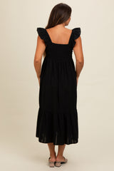 woman wearing a black maternity dress with ruffled straps and a tiered hem, showing a baby bump from the back