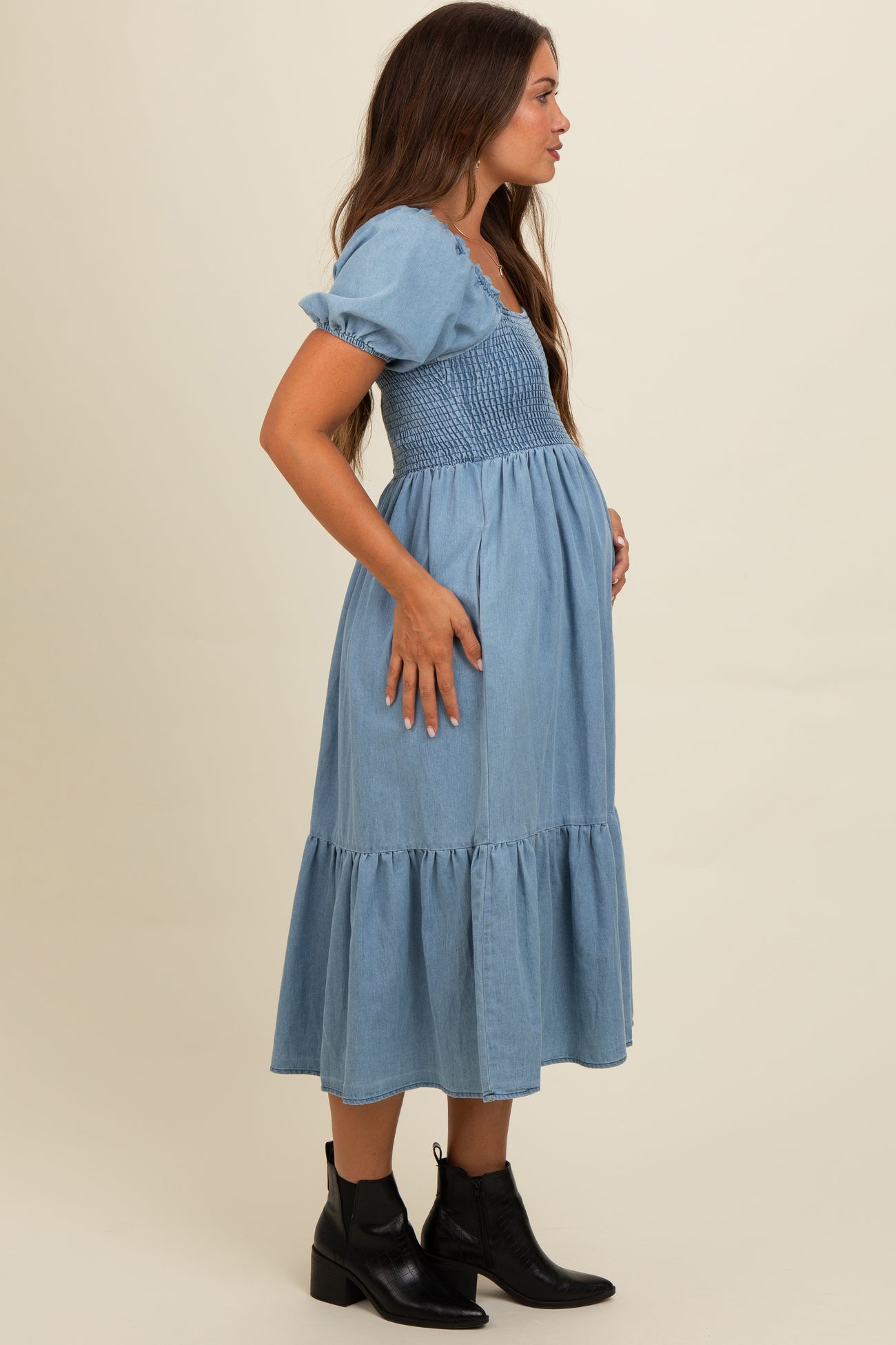 woman wearing a light blue maternity dress with puff sleeves and a tiered hem, showcasing her baby bump