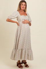 woman wearing a cream floral print maternity dress with puff sleeves and a tiered hem, showing her baby bump