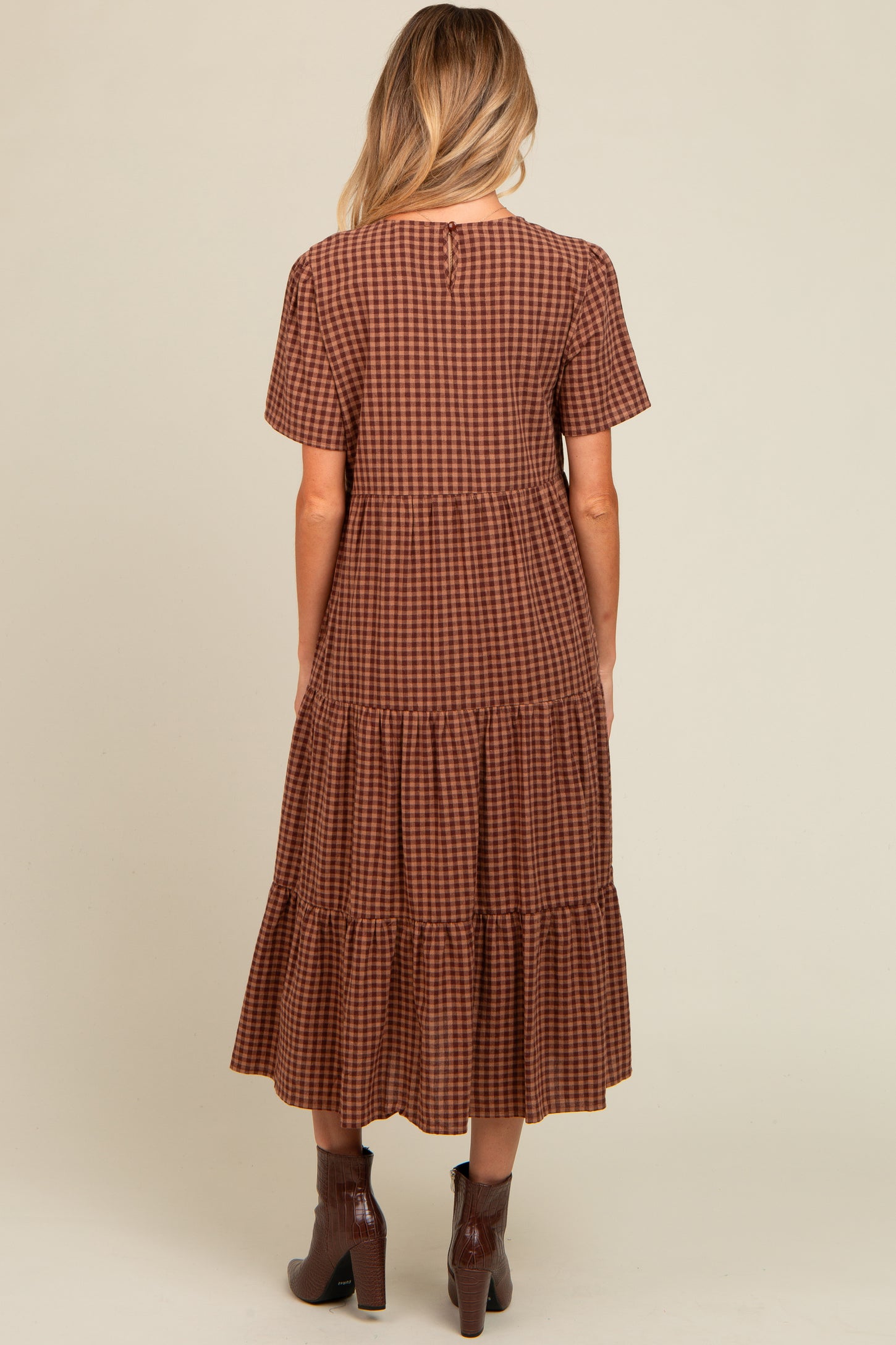 woman wearing a brown checkered maternity dress with short sleeves and tiered skirt, showing the back view