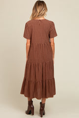 woman wearing a brown checkered maternity dress with short sleeves and tiered skirt, showing the back view