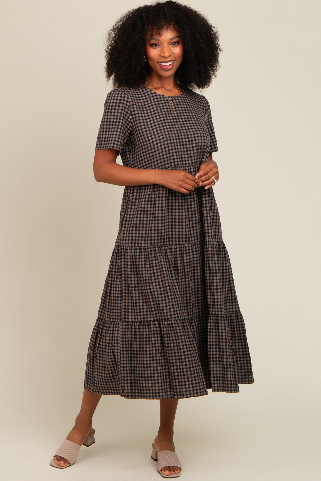 woman wearing a brown checkered tiered maxi dress with short sleeves and posing casually