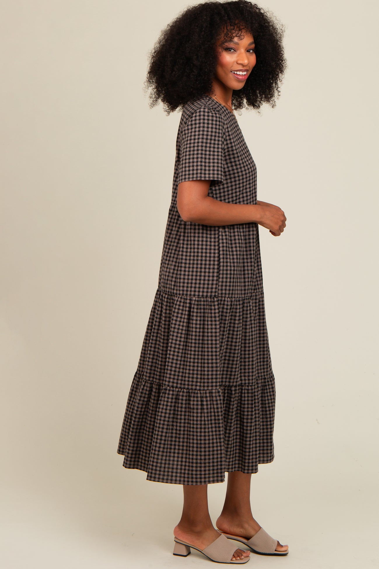woman wearing a brown and black checkered long sleeve tiered maxi dress and beige slide sandals