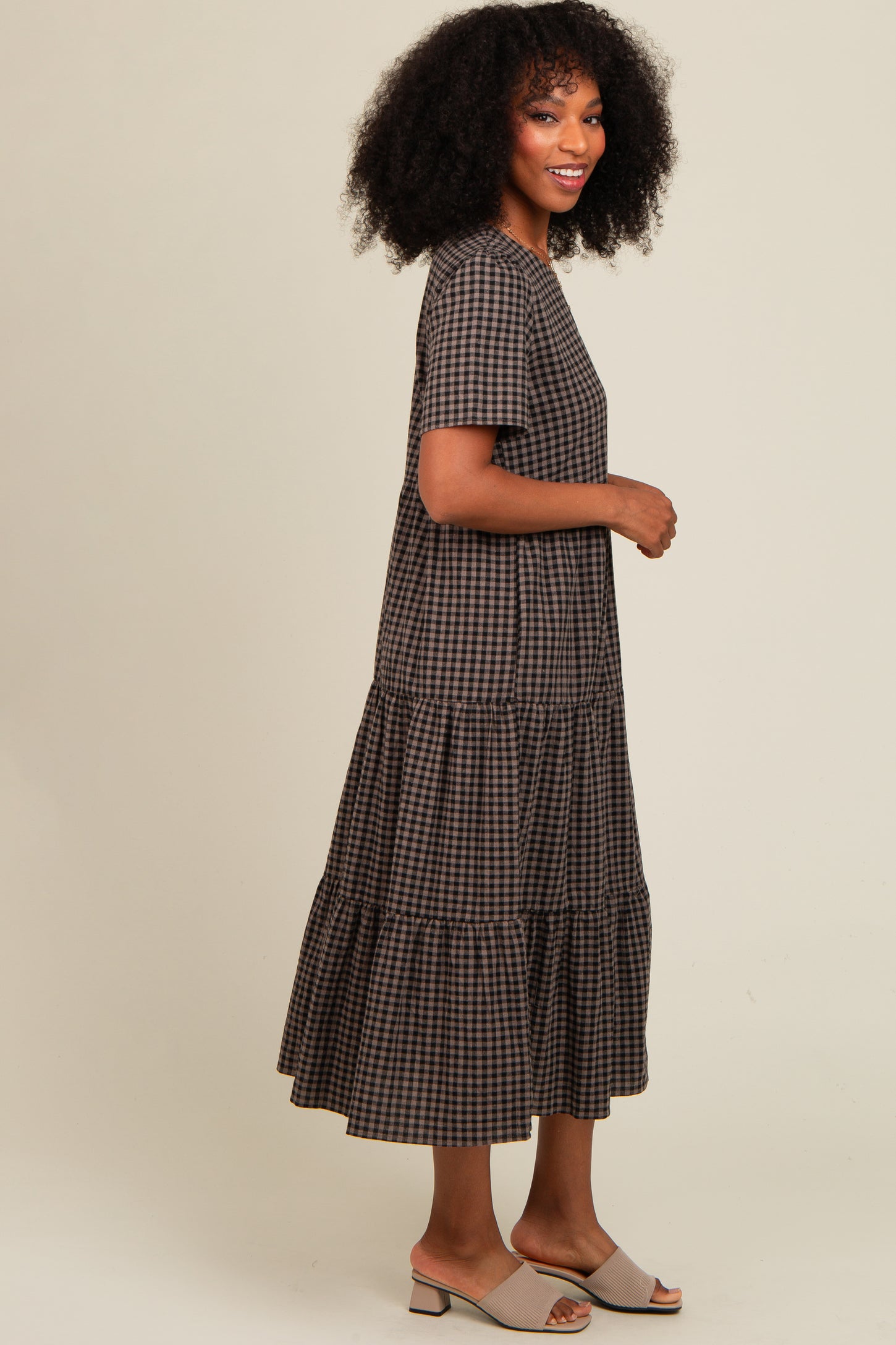 woman wearing a brown and black checkered long sleeve tiered maxi dress and beige slide sandals