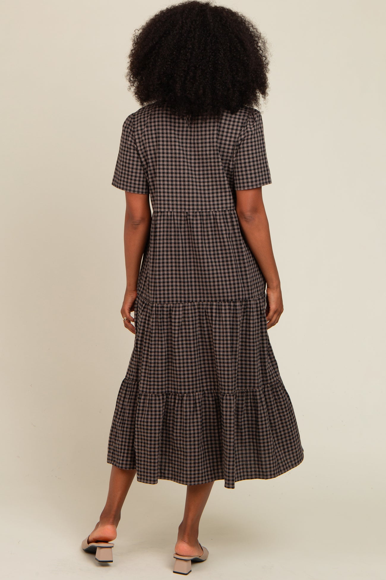 woman wearing a brown checkered tiered maxi dress with short sleeves and a flowy skirt, viewed from the back