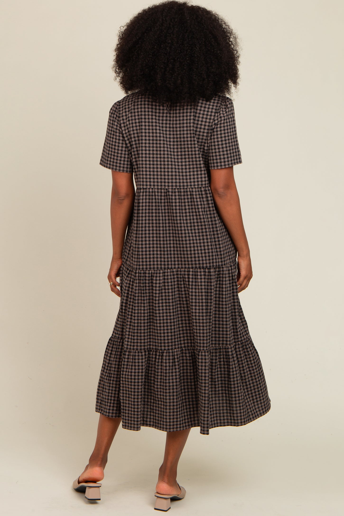 woman wearing a brown checkered tiered maxi dress with short sleeves and a flowy skirt, viewed from the back