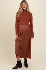 woman wearing a brown ribbed turtleneck maternity top and a flowy brown satin maternity skirt, with a visible baby bump