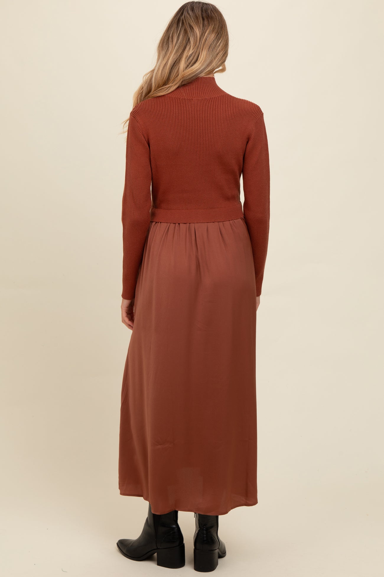 woman wearing a rust long sleeve maternity sweater with a flowy rust maxi skirt from the back