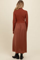 woman wearing a rust long sleeve maternity sweater with a flowy rust maxi skirt from the back