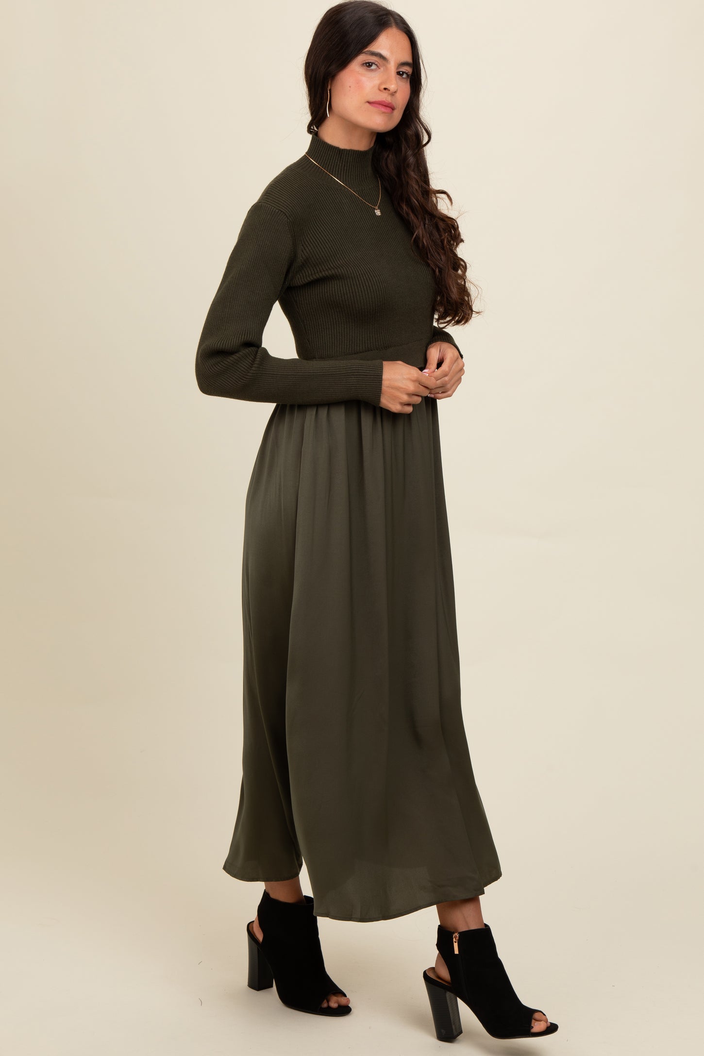 woman wearing a dark green ribbed long sleeve dress with a flowy skirt and black open-toe booties