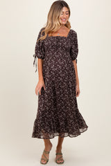 woman wearing a black floral maternity dress with short puff sleeves and a square neckline, smiling while standing