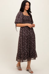 woman wearing a dark floral midi dress with a square neckline and puff sleeves, standing in a relaxed pose