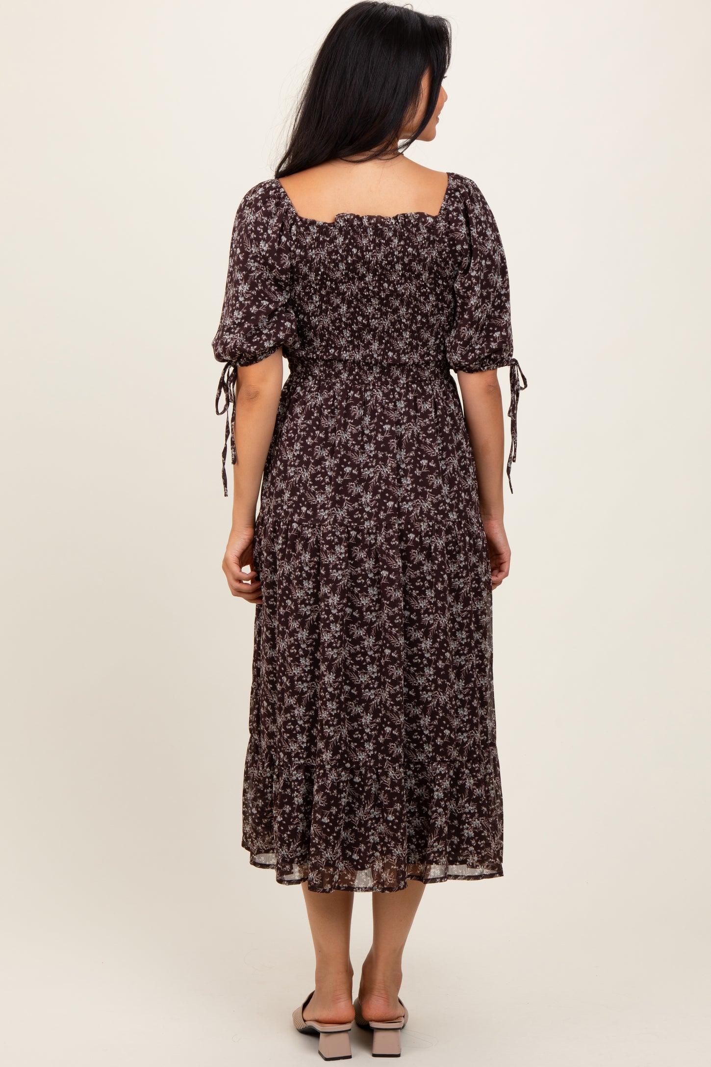 woman wearing a dark floral midi dress with puff sleeves and tie details, shown from the back
