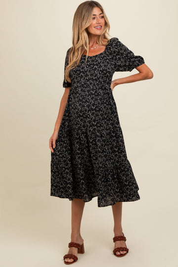 woman wearing a black floral maternity dress with puff sleeves and a flared skirt, showcasing her baby bump