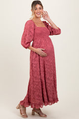 woman wearing a dusty rose maternity maxi dress with puff sleeves and a smocked bodice, holding her baby bump
