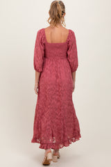 woman wearing a long pink maternity dress with puff sleeves and a smocked bodice, viewed from the back