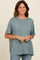 woman wearing a soft green short sleeve top with a relaxed fit and rolled sleeves