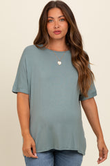 woman wearing a teal short sleeve maternity top with relaxed fit and a baby bump visible