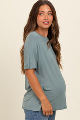 woman wearing a teal short sleeve maternity top with a visible baby bump