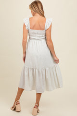 woman wearing a white floral maternity maxi dress with ruffle sleeves and a tiered skirt, showing her back