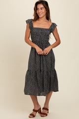 woman wearing a black floral midi dress with ruffled straps and a tiered skirt