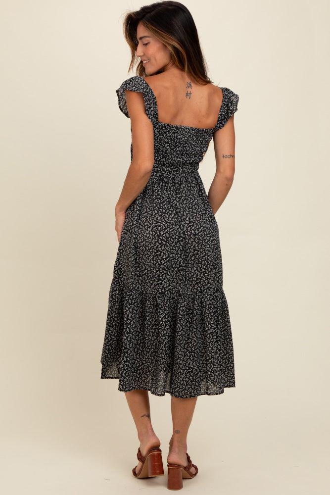 woman wearing a black floral midi dress with short ruffled sleeves and a smocked bodice, seen from the back