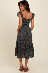 woman wearing a black floral midi dress with short ruffled sleeves and a smocked bodice, seen from the back