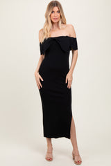 woman wearing a black off-the-shoulder maxi dress with a large bow detail and a side slit