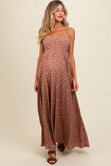 woman wearing a brown patterned maternity maxi dress with adjustable straps and a flowing silhouette, showing her baby bump